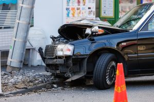 A car that collided with a utility pole and had its front end severely damaged and a leaning utility pole