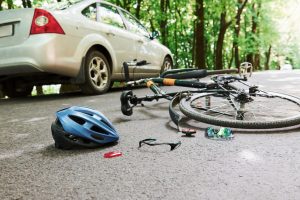 Bicycle and silver colored car accident on the road at forest at daytime